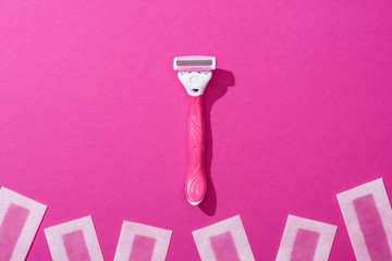 Wall Mural - top view of female shaver and depilation wax stripes on pink background