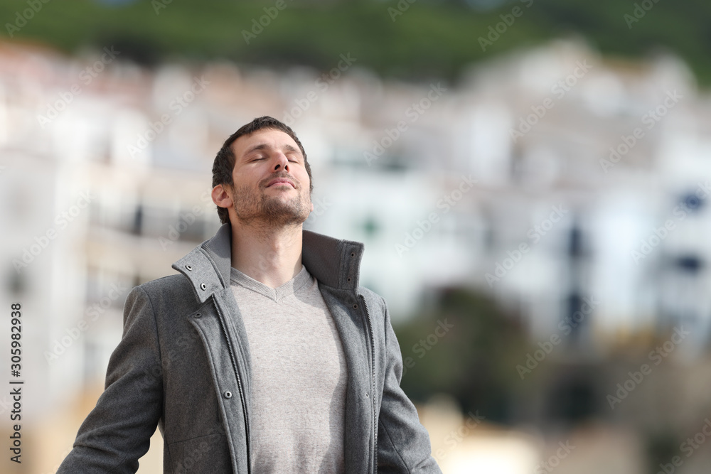 Adult man breaths deeply fresh air in a rural town in winter - obrazy, fototapety, plakaty 