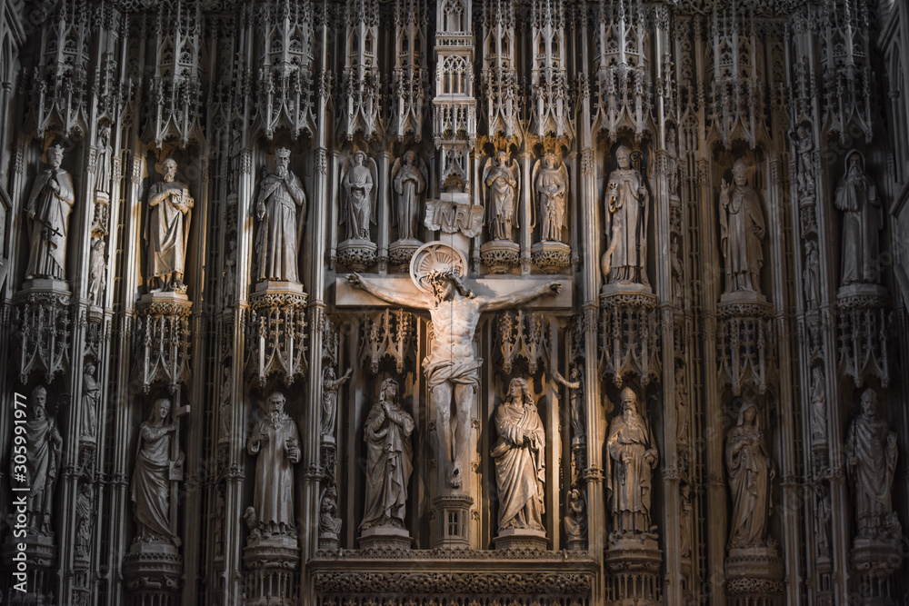 Jesus Christ on the cross in a cathedral or church interior surrounded by ornate stone carvings - obrazy, fototapety, plakaty 