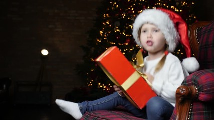 Poster - Cute little child with Christmas gift sitting in armchair at home