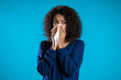 Young girl with afro hair sneezes into tissue. Isolated woman is sick, has a cold or has allergic reaction. Health, medicine, illness, treatment concept