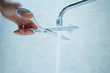 stop wasting the pure water, hand with scissors cut the water stream from faucet at home, environmental problem