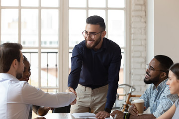 Young male team leader shaking hands with successful employee.