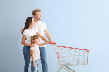 Canvas Print - Family with empty shopping cart on color background