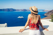 Woman traveler looking at Caldera from Fira or Thera, Santorini island, Greece. Tourism, traveling, vacation concept