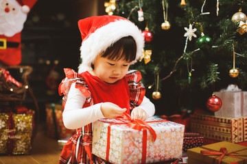 Wall Mural - toddler girl getting christmas gift in front of christmas tree