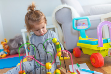 Toddler boy enjoys playing with toys in living room. Portrait of toddler boy enjoying toy. Toys for kids. Baby Boy Playing with Colorful toys.