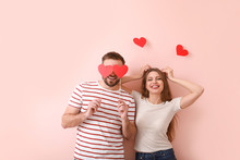 Happy Young Couple With Red Hearts On Color Background. Valentine's Day Celebration