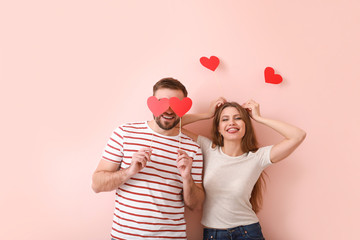 Happy young couple with red hearts on color background. Valentine's Day celebration