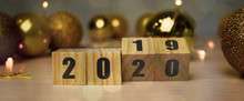 New Year Concept From 2019 To 2020. Business And Design Concept - Surreal Abstract Geometric Floating Wooden Cube With Word 2020 2019 Concept On Wood Floor And Christmas Background