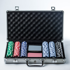 Suitcase with poker set on a light background