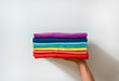 © iamtui7 - close up stack of folded multicolored t-shirt in hand over white background, copy space
