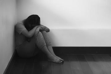 Wall Mural - A young woman suffering from depression Sitting on the wooden floor in the room alone.