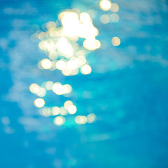 Wall Mural - Bokeh light effects over a rippled, blue water background