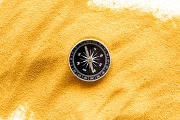 Wall Mural - Travel concept. Compass on yellow sand background top view copy space