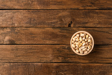 Delicious Pistachios In Bowl On Wooden Background With Copyspace. Top View