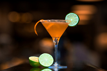 orange cocktail topped with lime slice