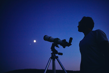 Wall Mural - astronomer with a telescope watching at the stars and moon. my astronomy work.