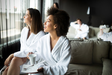 Woman relaxing and drinking tea in robes during wellness