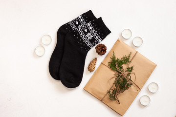 New year 2020 flatlay. Christmas black ornamental socks, gift box in eco kraft paper with pine tree cones. Mock up template design. Winter holiday decorations, minimal style,white background. Top view