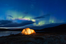 Northern Lights Dancing Over An Iluminated Tent In Norway