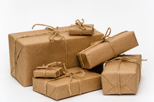 Pile Of Stacked Boxes Wrapped With Brown Kraft Paper And Tied With Twine On A White Background. Logistic And Package Concept. Close-up