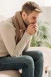 © LIGHTFIELD STUDIOS - sick man in warm scarf coughing in folded hands while sitting on sofa