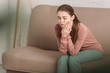 © LIGHTFIELD STUDIOS - unhappy girl sitting on sofa and suffering from toothache