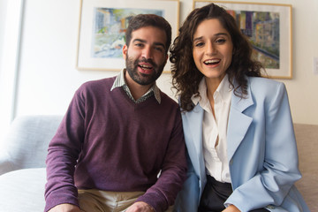 Front portrait of happy couple saying Hi at gadget screen. Young man and woman in casual looking at camera and smiling. Video call users concept