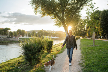 young man takes his beloved dog for a walk in the park at sunset - millennial in a moment of relaxat