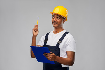 Poster - profession, construction and building - thinking indian worker or builder in helmet with clipboard and pencil having idea over grey background