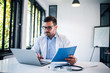 © bnenin - Portrait of handsome doctor working with laptop and documents.
