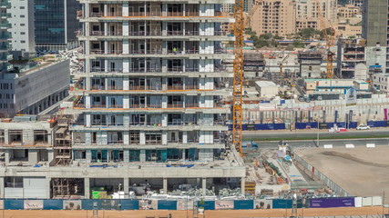 Wall Mural - Aerial view of a skyscrapers under construction with huge cranes timelapse in Dubai.