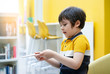 © Anchalee - Side viiew portrait of active kid with smiling face holding card game, Child boy playing training card inth classroom at schoool, Develoment and Education concept