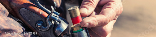 Fotografía Close up of hunter loading shotgun, holds a gun and ammunition in his hand