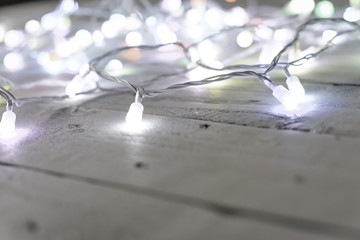 Christmas tree lights or fairy lights over festive white wooden board background with copy space