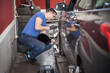 © guruXOX - Wheel alignment. Car mechanic installing sensor during suspension adjustment
