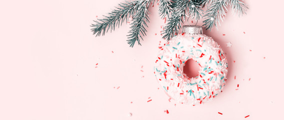 christmas toy donut with sugar sprinkling hanging on christmas tree branch, banner format