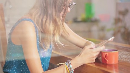 Woman using cellphone inside house and drinking coffee / tea.