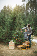 © sofiko14 - Mother and her little son decorating Christmas tree outdoors in winter forest. New Year, Christmas and family concept