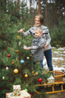 © sofiko14 - Merry Christmas and Happy Holidays. Mom and son decorate the Xmas tree outdoors. Wooden sledge and presents, Christmas wreath