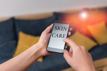 Word writing text Skin Care. Business photo showcasing things that you do or use to keep your skin healthy and attractive woman using smartphone office supplies technological devices inside home