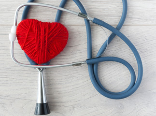 Red heart with stethoscope on white wood background. Medical health care.