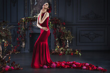 Attractive Gorgeous Brunette Woman In Red Evening Dress With Plume In Dark Luxury Interior In Vintage Barocco Style Decorated Flowers
