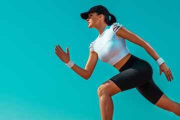 Wall Mural - Athlete runner and sprinter. Girl fit athlete running on the sky background. The concept of a healthy lifestyle and sport. Woman in black and white sportswear.