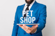© Artur - Conceptual hand writing showing Pet Shop. Concept meaning Retail business that sells different kinds of animals to the public Businessman in blue suite with a tie holds lap top in hands