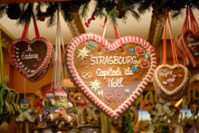 Gingerbread Cookies In Shape Of Hearts Hanging From Stall With Messages Of Christmas, Love And Strasbourg And A Gingerbread Man At The Strasbourg Christmas Market