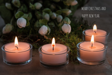 Christmas card with four burning tealights, Christmas rose buds, moss and Christmas and New Year´s greetings in white letters g  