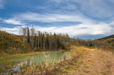 Wall Mural - autumn landscape in the mountains, a small lake wild impassable natural places, white clouds in the blue sky