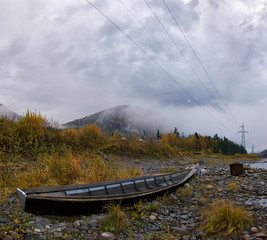 Wall Mural - autumn landscape in the mountains, a large wooden old boat on the Bank of the Tom river, fog and rainy clouds